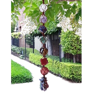 May include: A seven-stone crystal chakra hanging with a brown leather cord. The stones are clear, amethyst, blue, green, tiger's eye, red, and pink.