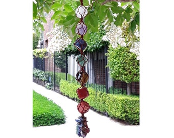 May include: A seven-stone crystal chakra hanging with a brown leather cord. The stones are clear, amethyst, blue, green, tiger's eye, red, and pink.