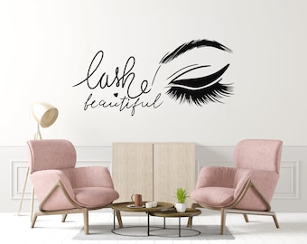 Può includere: Un soggiorno rosa con due poltrone, un tavolino da caffè e un adesivo da parete che dice "lashes! beautiful" con un occhio stilizzato e ciglia.