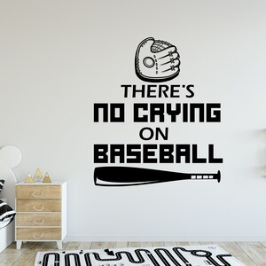 Op de afbeelding: Zwart-witte baseball-thema wanddecoratie met een honkbalhandschoen, knuppel en de tekst "There's no crying on baseball".