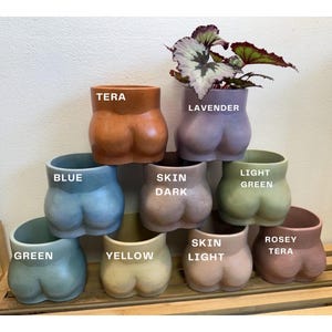 May include: A set of three ceramic mugs with a speckled, matte finish. Each mug features a different color: light blue, cream, and gray. The mugs have a simple, modern design and a comfortable handle.