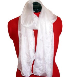 Puede incluir: Una bufanda blanca y transparente drapeada sobre un maniquí rojo. La bufanda está hecha de una tela ligera y fluida.
