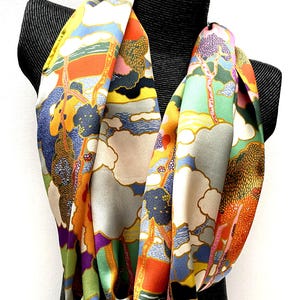May include: A colorful silk scarf with a whimsical design featuring trees, clouds, and a landscape. The scarf is a vibrant mix of orange, yellow, green, blue, and purple.