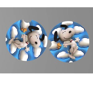 May include: Two car coasters featuring Snoopy from Peanuts. Each coaster has a blue background with white clouds and Snoopy in a playful pose. One Snoopy is lying down, and the other is jumping. A small yellow bird is also present.