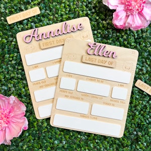 May include: Two wooden signs with blank spaces for writing. The signs are decorated with stars and animal illustrations. The top sign says "Annalise First Day" and the bottom sign says "Ellen Last Day Of".