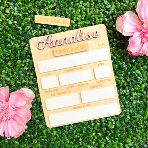 May include: A wooden sign with the words "LAST DAY OF" and "FIRST DAY OF" on it. The sign is decorated with a pink star and a pink cat. The sign is personalized with the name "Annalise".