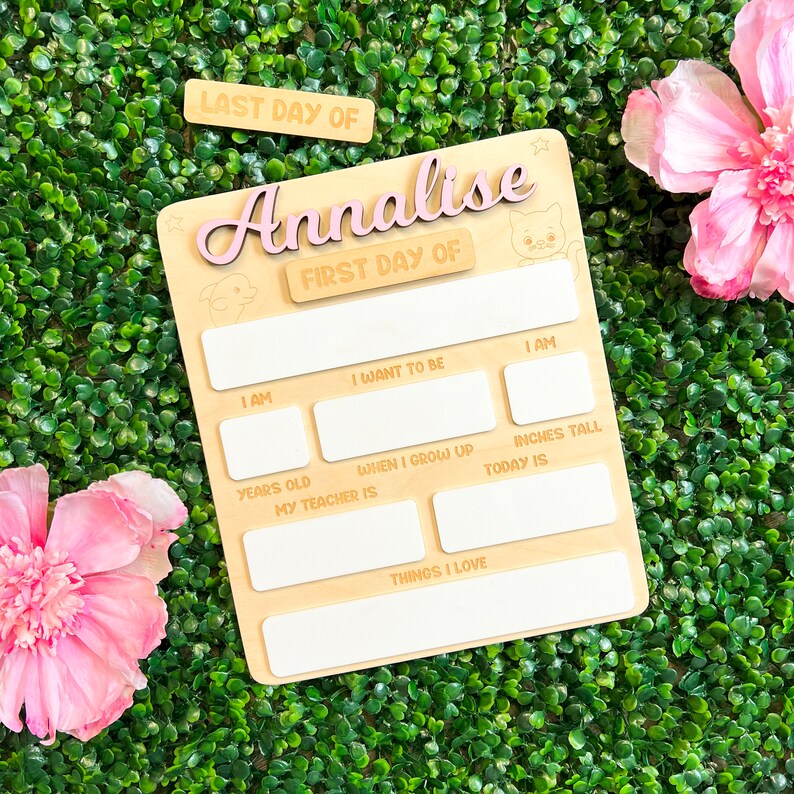 May include: A wooden sign with the words "LAST DAY OF" and "FIRST DAY OF" on it. The sign is decorated with a pink star and a pink cat. The sign is personalized with the name "Annalise".