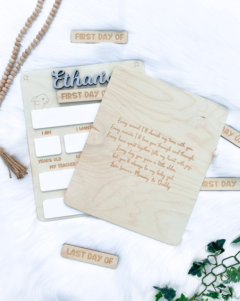 May include: A wooden plaque with a personalized message for a child's first day of school. The plaque has a space to fill in the child's age, teacher's name, and other details. The message reads: "Every second I'll cherish my time with you. Every minute I'll love you through and through. Every hour spent together fills my heart with joy. Every day you grow a little older, but you'll always be my baby girl. Love forever. Mommy & Daddy."