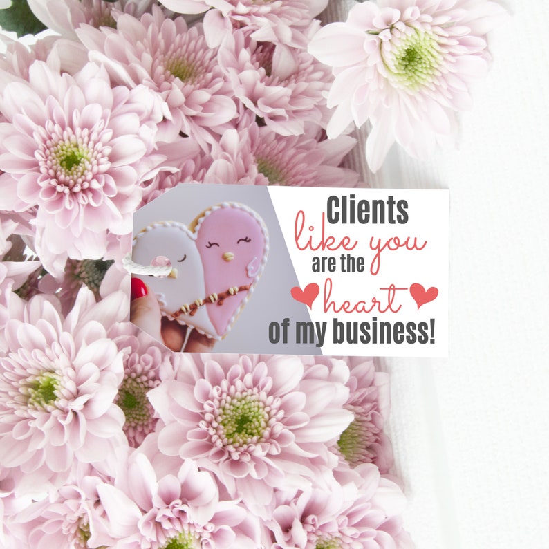 Puede incluir: Una tarjeta blanca con corazones rosas y el texto "Clientes como t&uacute; son el coraz&oacute;n de mi negocio!" La tarjeta est&aacute; colocada sobre un ramo de flores rosas.