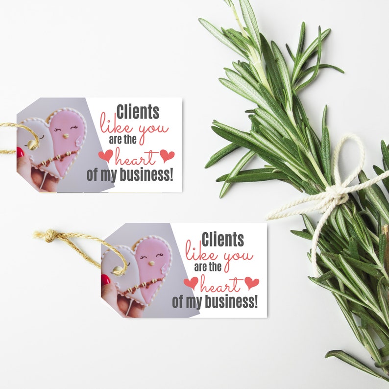 Puede incluir: Dos etiquetas de regalo con un dise&ntilde;o de galleta en forma de coraz&oacute;n y el texto "Clients like you are the heart of my business!" impreso en ellas.