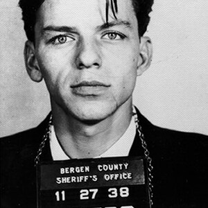 May include: Black and white mugshot of a man with dark hair. The photo is labeled "Bergen County Sheriff's Office" with the numbers "11 27 38" underneath.