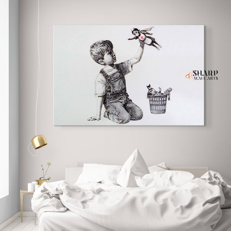 Pu&ograve; includere: Un'illustrazione in bianco e nero di un bambino piccolo inginocchiato e che alza la mano per prendere una piccola bambola di supereroe che vola sopra di lui. La bambola indossa un mantello rosso e una croce rossa sul petto. Un bidone della spazzatura si trova sullo sfondo con altri giocattoli al suo interno.