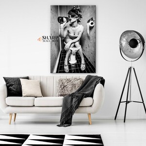 May include: Black and white photo of a woman sitting on a toilet in a bathroom, drinking from a bottle. The woman is wearing sunglasses and has her hair up in a bun. The photo is printed on a canvas.