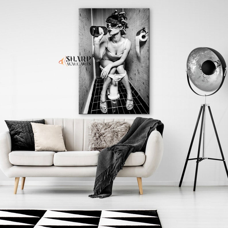 May include: Black and white photo of a woman sitting on a toilet in a bathroom, drinking from a bottle. The woman is wearing sunglasses and has her hair up in a bun. The photo is printed on a canvas.