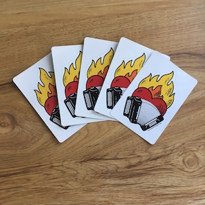 May include: Five white stickers featuring a black and white illustration of a red heart on fire with a black accordion on top.