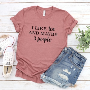 May include: A mauve t-shirt with the text "I like tea and maybe 3 people" printed in black.