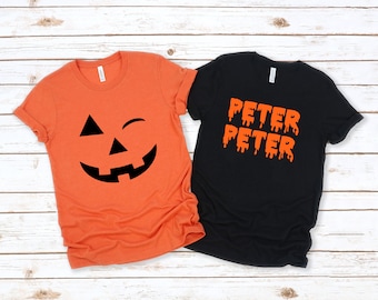 May include: Two Halloween themed t-shirts. One orange t-shirt with a black jack-o-lantern face and the other black t-shirt with the word "PETER" written twice in orange dripping letters.