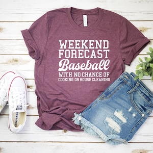May include: Burgundy t-shirt with white text that reads "Weekend Forecast Baseball with no chance of cooking or house cleaning".