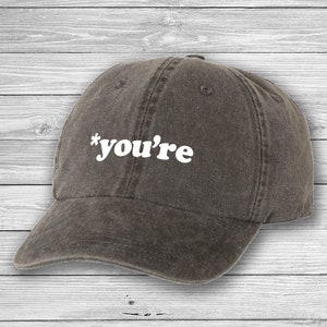 May include: A dark gray baseball cap with the text "*you're" in white on the front.
