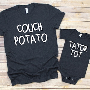 May include: A dark gray t-shirt with the text "COUCH POTATO" in white lettering and a matching dark gray baby onesie with the text "TATOR TOT" in white lettering.