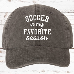 May include: A gray baseball cap with the text "SOCCER is my FAVORITE season" in white. The cap has a curved brim and a classic, casual style, perfect for sports enthusiasts.