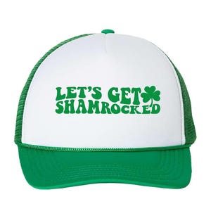 以下が含まれることがあります： 白と緑のトラッカーハットに「Let's Get Shamrocked」の文字とクローバーのグラフィックが描かれています。