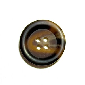 May include: A large, round button with four holes. The button has a dark brown outer ring and a lighter brown centre with a marbled effect. The button is set against a white background.