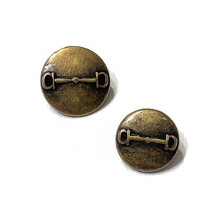 Pode incluir: Um par de brincos de metal dourado com um design de freio.