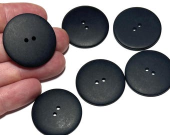 Può includere: Una collezione di sei grandi bottoni rotondi neri opachi. Ogni bottone ha due piccoli fori per cucire. I bottoni sono realizzati in un materiale solido e sono adatti a vari progetti di cucito.
