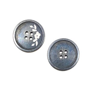 May include: Two round, dark gray buttons with four holes each. One button has a white floral design.