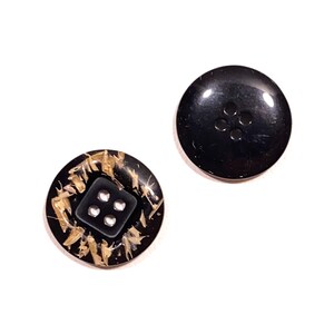 May include: Two black buttons with four holes each. One button has a gold flecked design.
