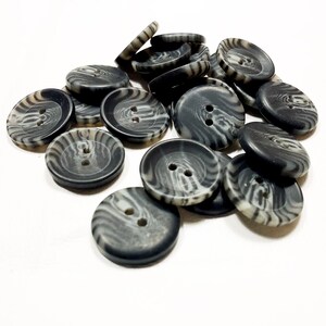 Peut inclure: Un tas de boutons rayés noirs et blancs. Les boutons sont en plastique et ont deux trous.