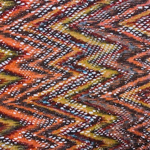 May include: Close-up of a fabric with a chevron pattern. The design features a mix of colours, including orange, brown, yellow, and white. The fabric has a textured appearance, with small white dots creating a visual contrast.