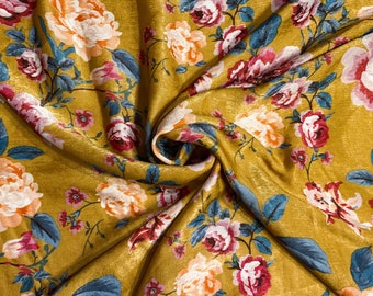 May include: A mustard yellow fabric with a floral print featuring pink, white, and blue roses. The fabric has a subtle sheen and a soft texture.