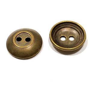 May include: Two antique gold-toned buttons with two holes each. The button on the left is flat, while the button on the right has a raised, textured rim.