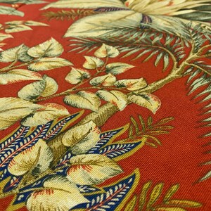 May include: Red fabric with a tropical leaf pattern. The leaves are green, yellow, and blue. The fabric has a textured surface.