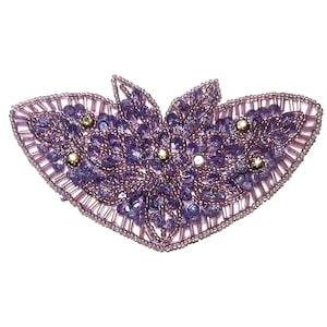 May include: A decorative, beaded applique in a butterfly shape. The applique features a combination of purple beads, sequins, and seed beads, with gold and silver accents. The edges are outlined with small, silver beads.