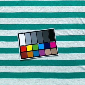 Puede incluir: Un primer plano de una muestra de tela a rayas de color turquesa y blanco con una tabla de colores para fotograf&iacute;a digital.