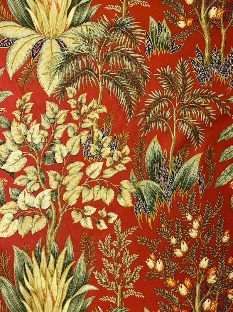 May include: Red fabric with a repeating pattern of green and yellow tropical plants. The pattern includes palm trees, ferns, and flowers.