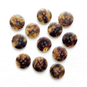 May include: Twelve brown and beige swirl patterned buttons with four holes each.