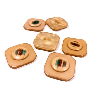 May include: Six square-shaped buttons with a raised center. The buttons are a light beige color with a brown and green design on the center. Two of the buttons have a plain center with two holes.