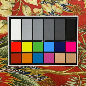 May include: A color chart with 24 color swatches, including white, black, red, yellow, green, blue, brown, orange, and pink. The chart is labeled "Digital Kolor Kord 5 x 7" and "DKK".
