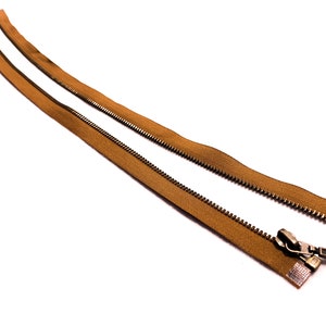 May include: A brown zipper with a metal slider and teeth. The zipper is open and the two sides are separated.