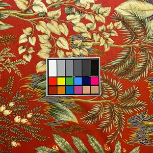 May include: Red fabric with a floral pattern featuring green and gold leaves and white flowers. A color chart is included in the image.