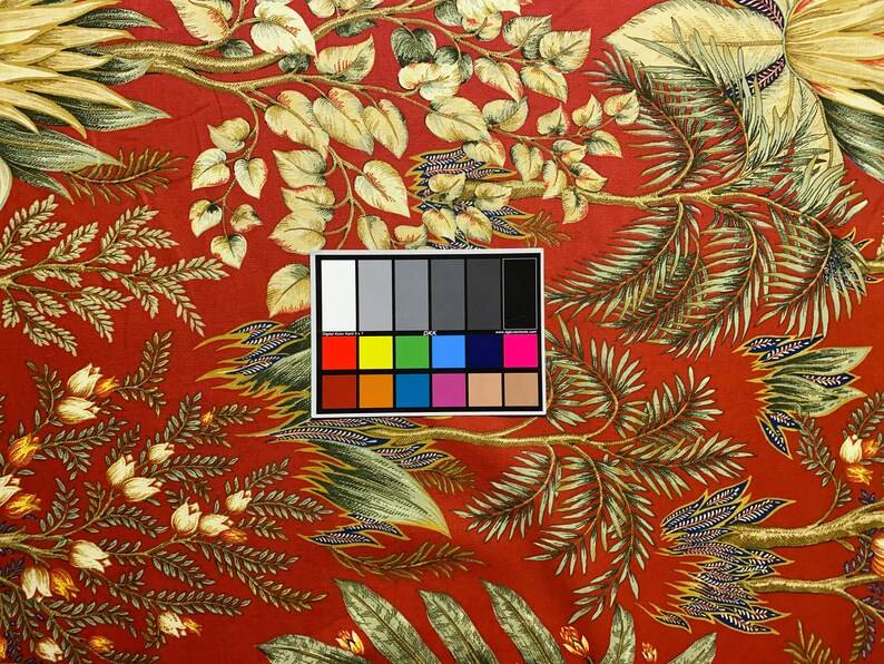 May include: Red fabric with a floral pattern featuring green and gold leaves and white flowers. A color chart is included in the image.