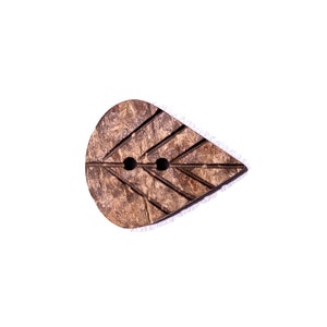 Peut inclure: Un bouton en coquille de noix de coco marron en forme de larme avec un motif de feuille. Le bouton a deux trous pour la couture.