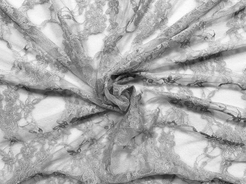 May include: A close-up of a delicate, gray lace fabric with a floral pattern. The fabric is soft and flowing, creating a romantic and elegant look.