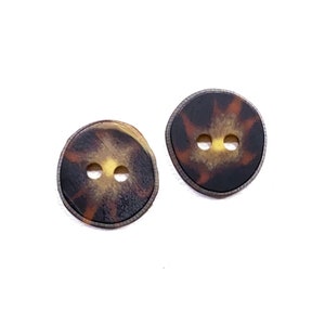 May include: Two brown and yellow patterned buttons with two holes each.