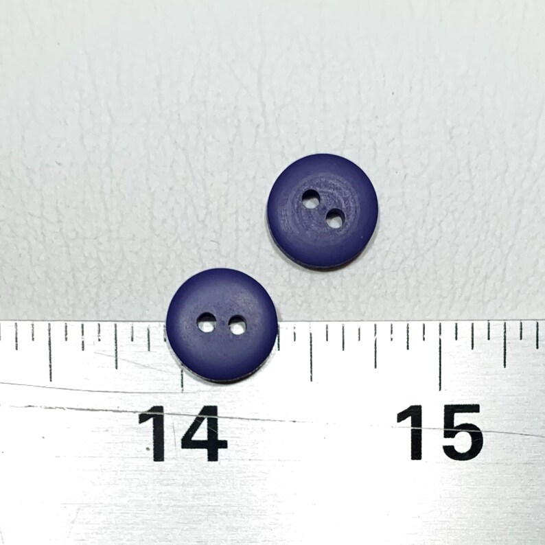 May include: Two dark blue plastic buttons with two holes each. The buttons are about 1/2 inch in diameter.
