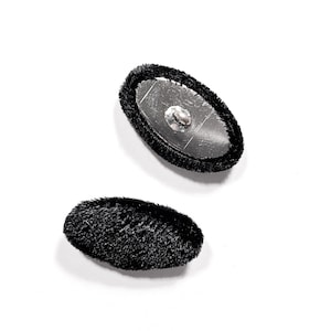 May include: Two black oval-shaped buttons with a fuzzy texture. One button has a silver backing with a small metal loop.